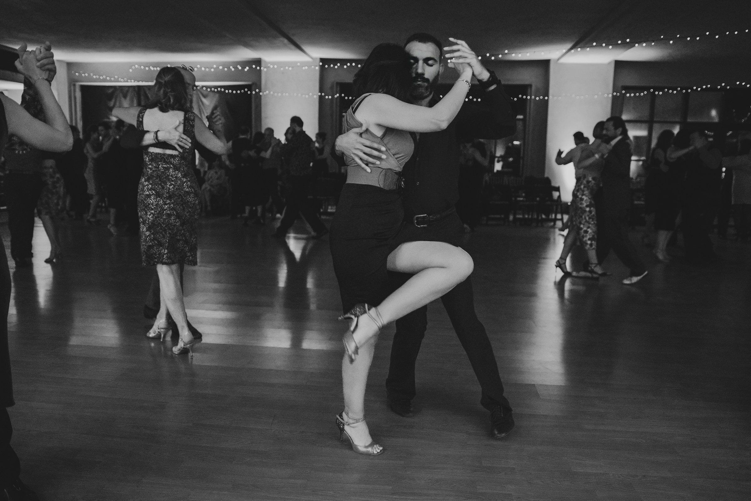 A couple dancing tango in a dimly lit social hall
